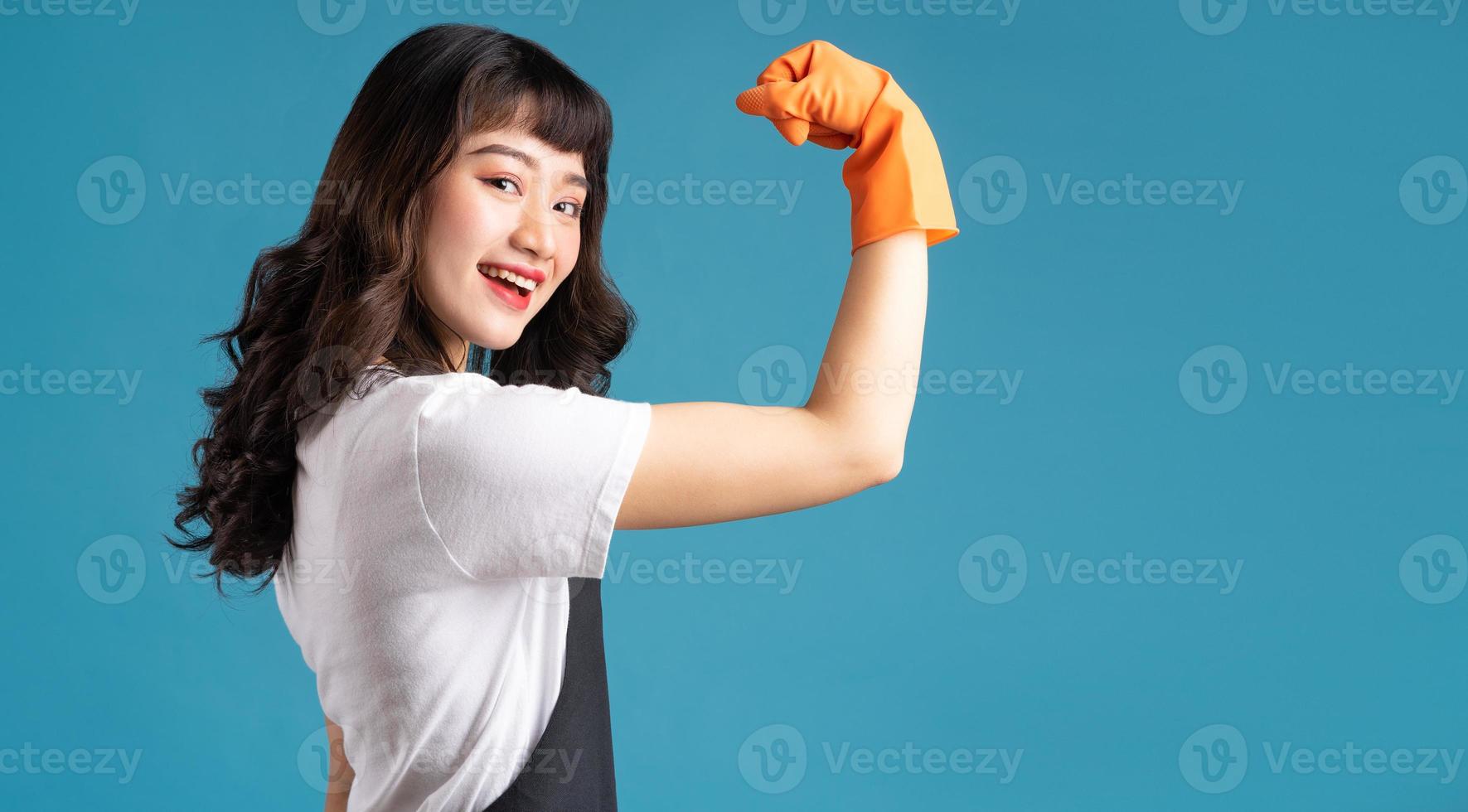 een foto van een Aziatische vrouw in een schort en handschoenen die zich voorbereiden op de schoonmaakklus