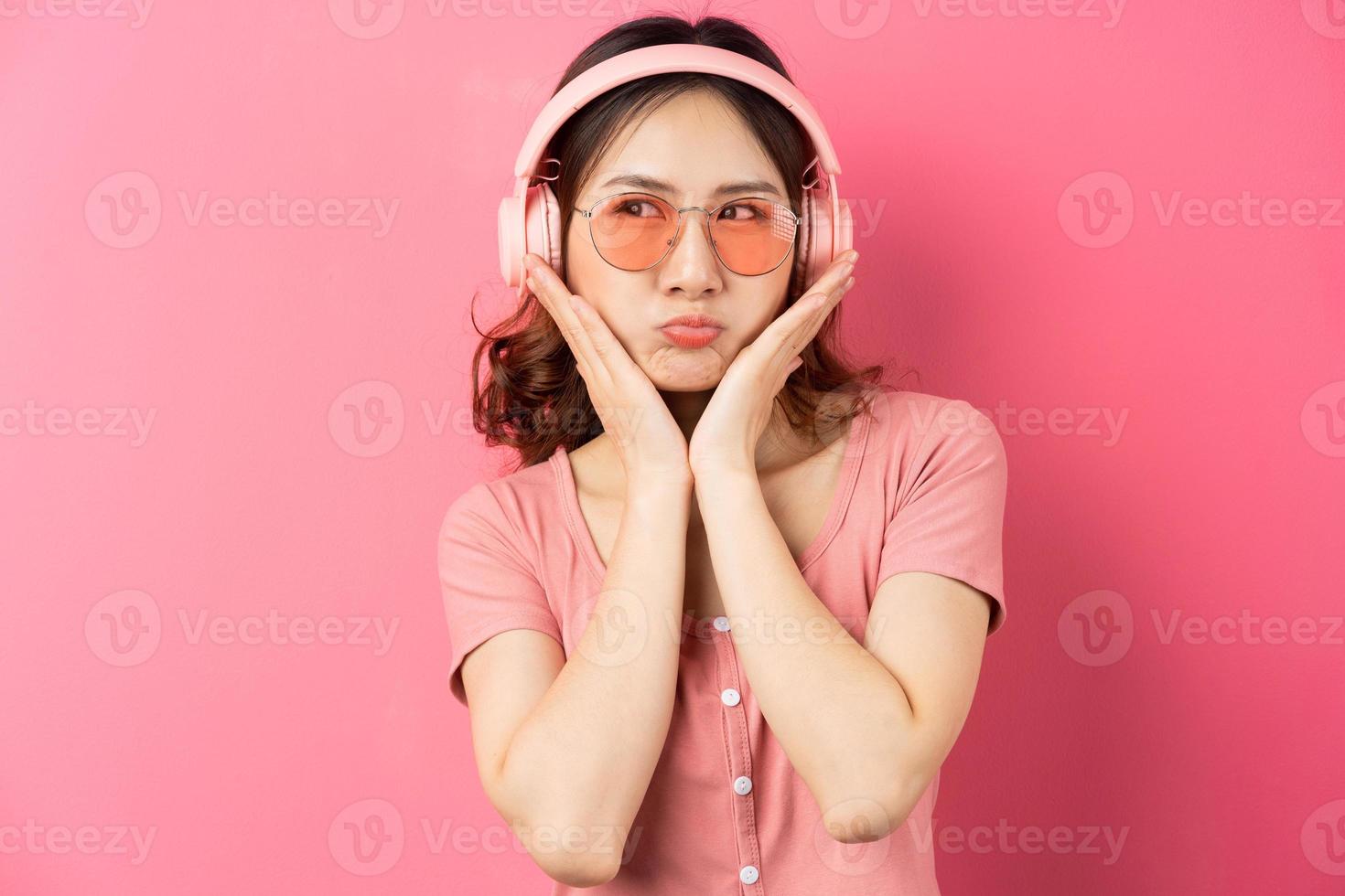 mooi jong meisje met een roze koptelefoon op een roze achtergrond foto