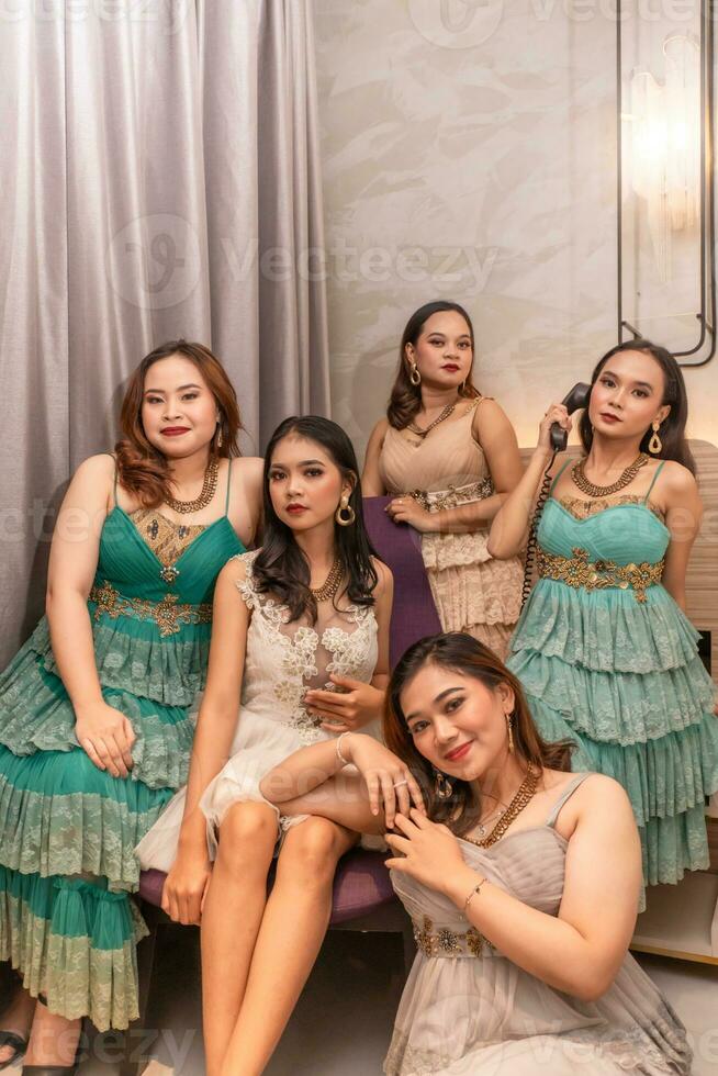 een groep van Aziatisch Dames in luxueus jurken zijn aan het wachten voor avondeten in een hotel balzaal foto
