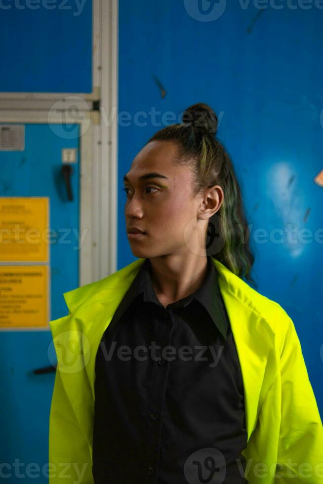 een Aziatisch Mens met lang gekruld haar- is poseren in voorkant van een blauw garderobe foto