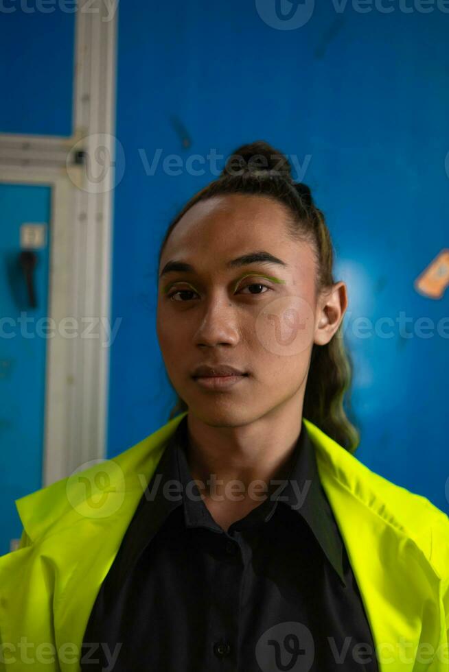 een Aziatisch Mens met lang gekruld haar- is poseren in voorkant van een blauw garderobe foto