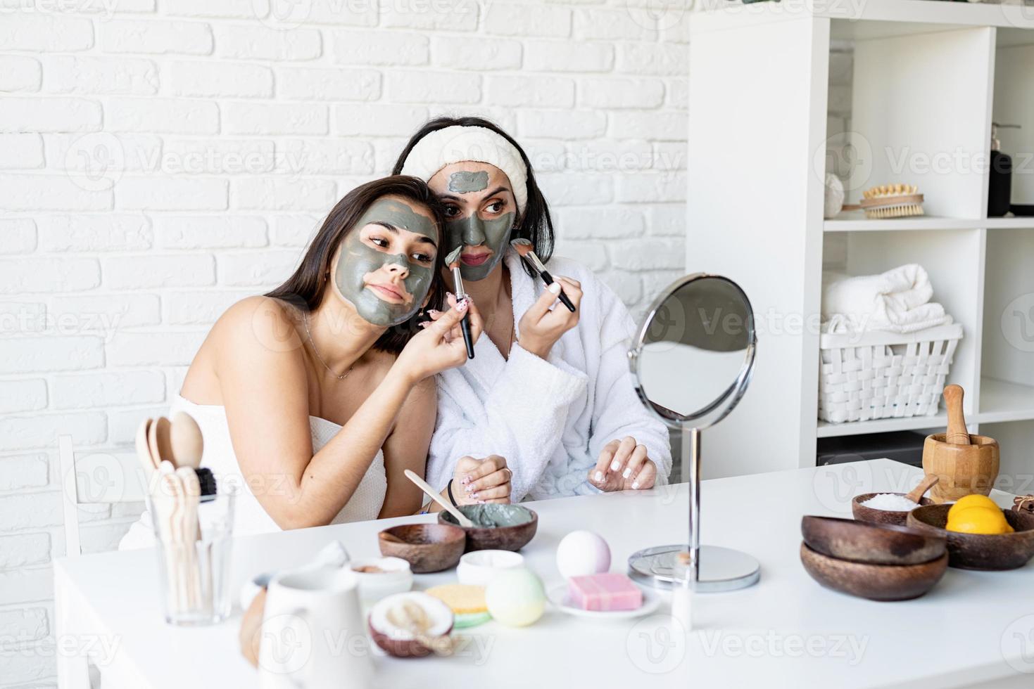 twee mooie vrouwen die een gezichtsmasker toepassen met plezier foto