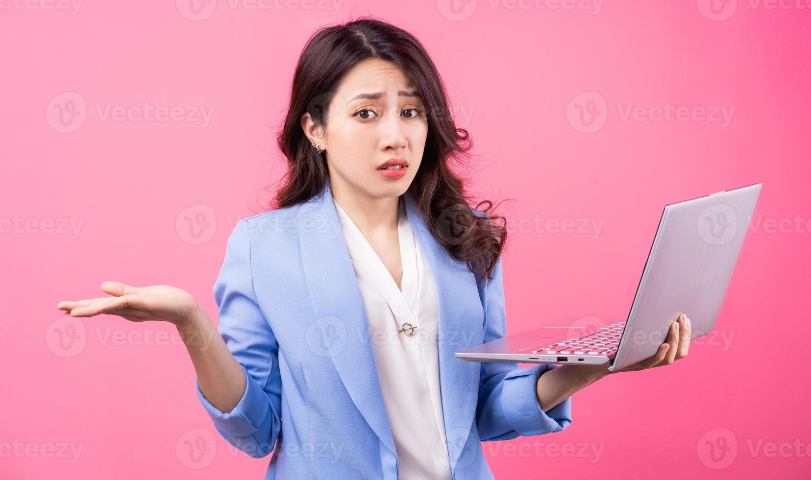 Aziatische zakenvrouw met laptop op roze achtergrond foto