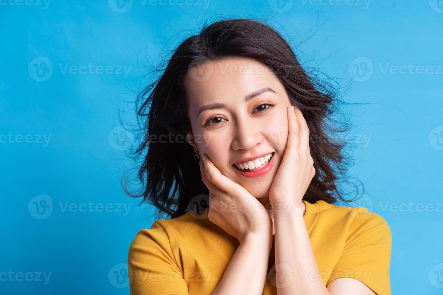 de mooie Aziatische vrouw glimlachte en omhelsde haar gezicht met beide handen foto