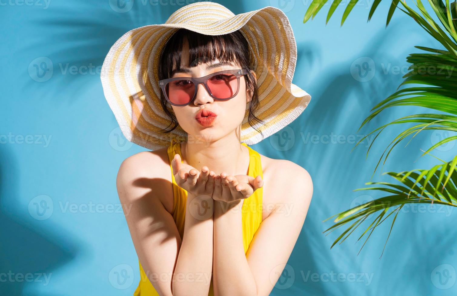 mooie aziatische vrouw die gele jumpsuit op blauwe achtergrond draagt en, zomerconcept foto