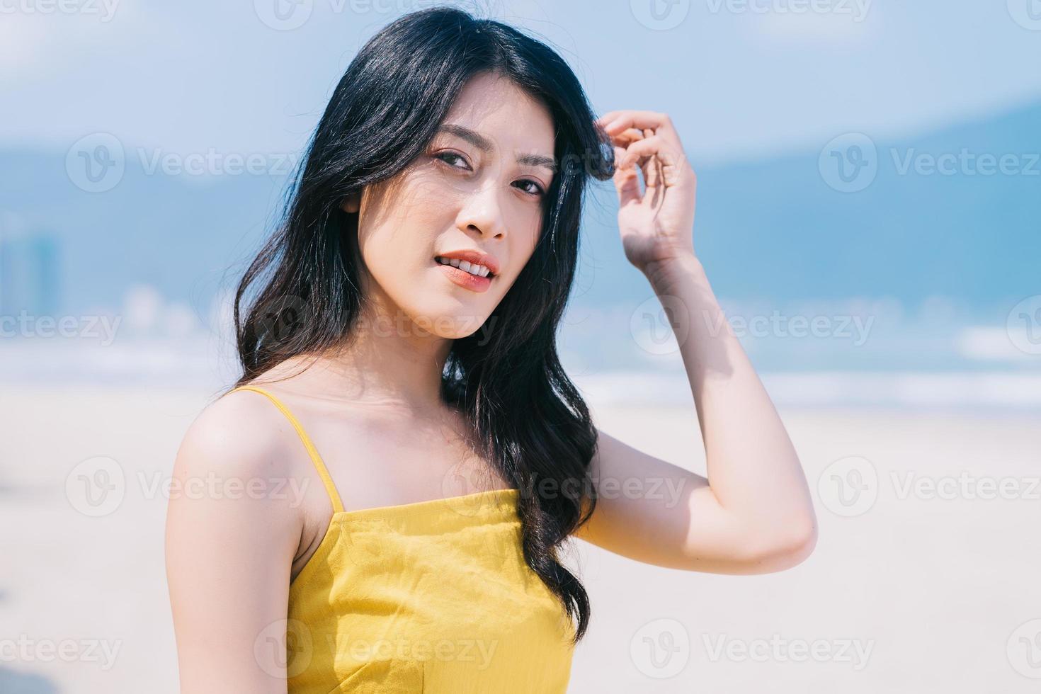 jonge aziatische vrouw die van de zomervakantie op het strand geniet foto
