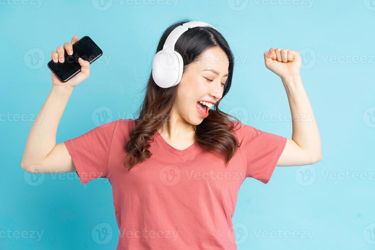 mooie aziatische vrouw die witte draadloze hoofdtelefoons draagt en telefoon in haar hand houdt terwijl ze op muziek danst foto