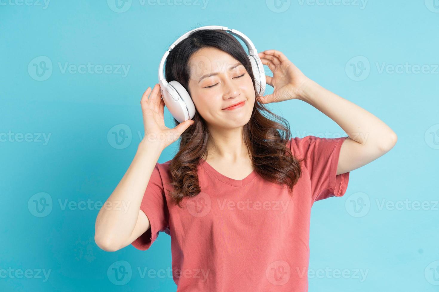 mooie aziatische vrouw die witte draadloze hoofdtelefoons draagt en telefoon in haar hand houdt terwijl ze op muziek danst foto