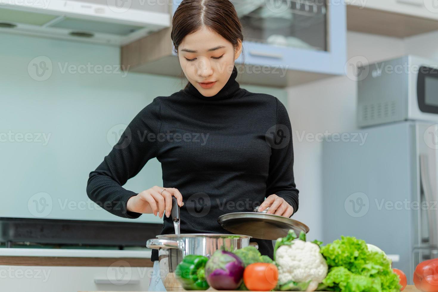 vrouw kijkt naar de soep die ze aan het koken is foto