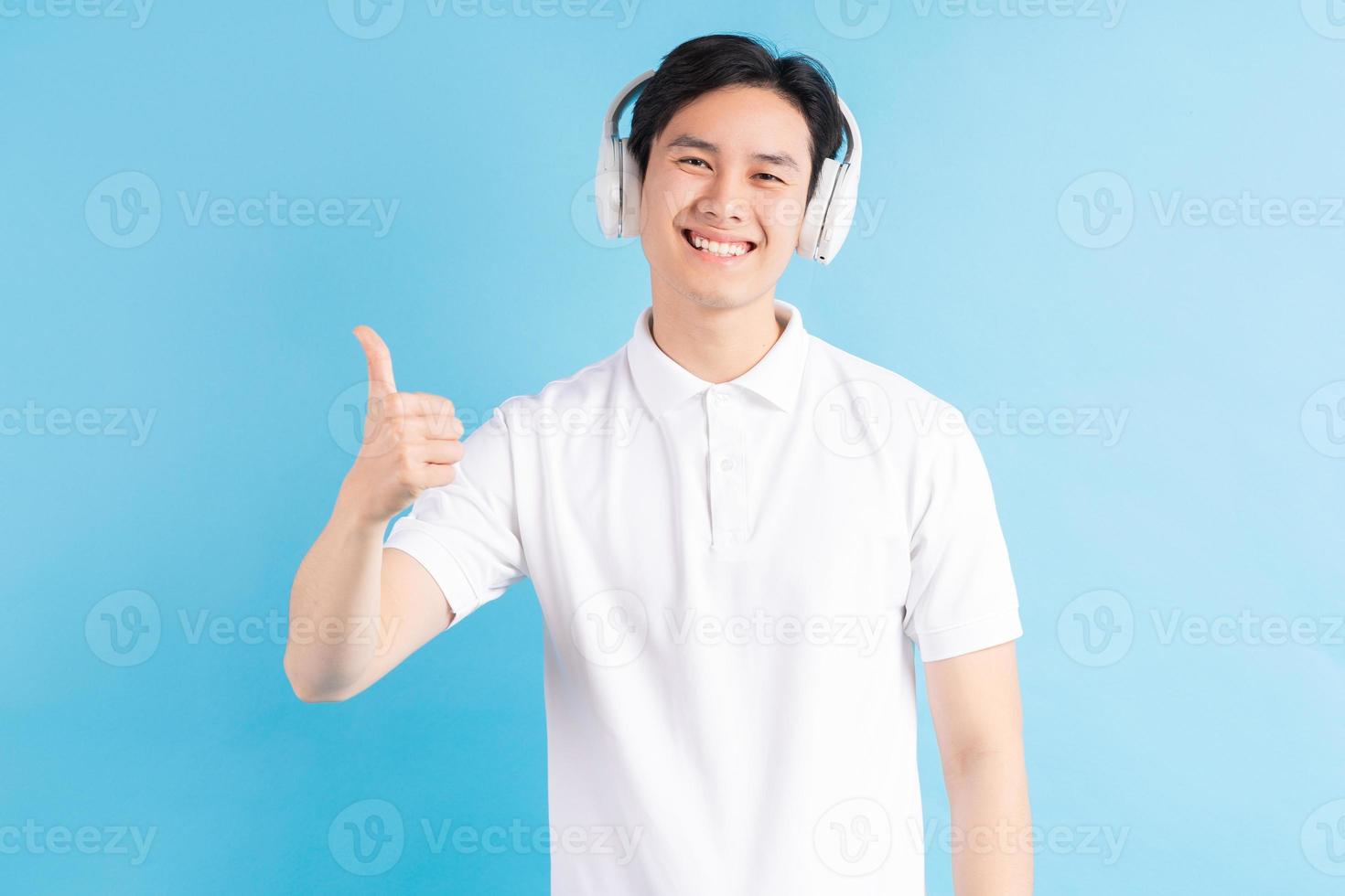Aziatische man die naar muziek luistert en zijn duimen omhoog gebruikt foto