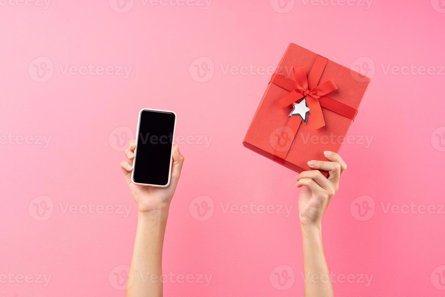 handen met rode geschenkdoos en telefoon foto