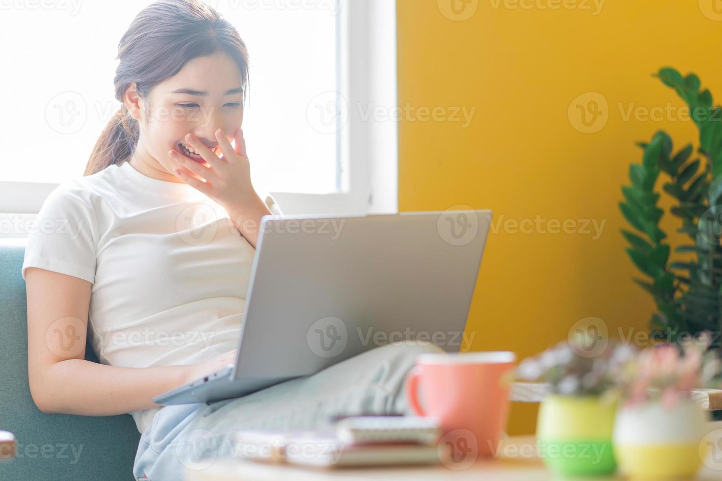 jonge aziatische vrouw die op de bank zit en thuis werkt foto