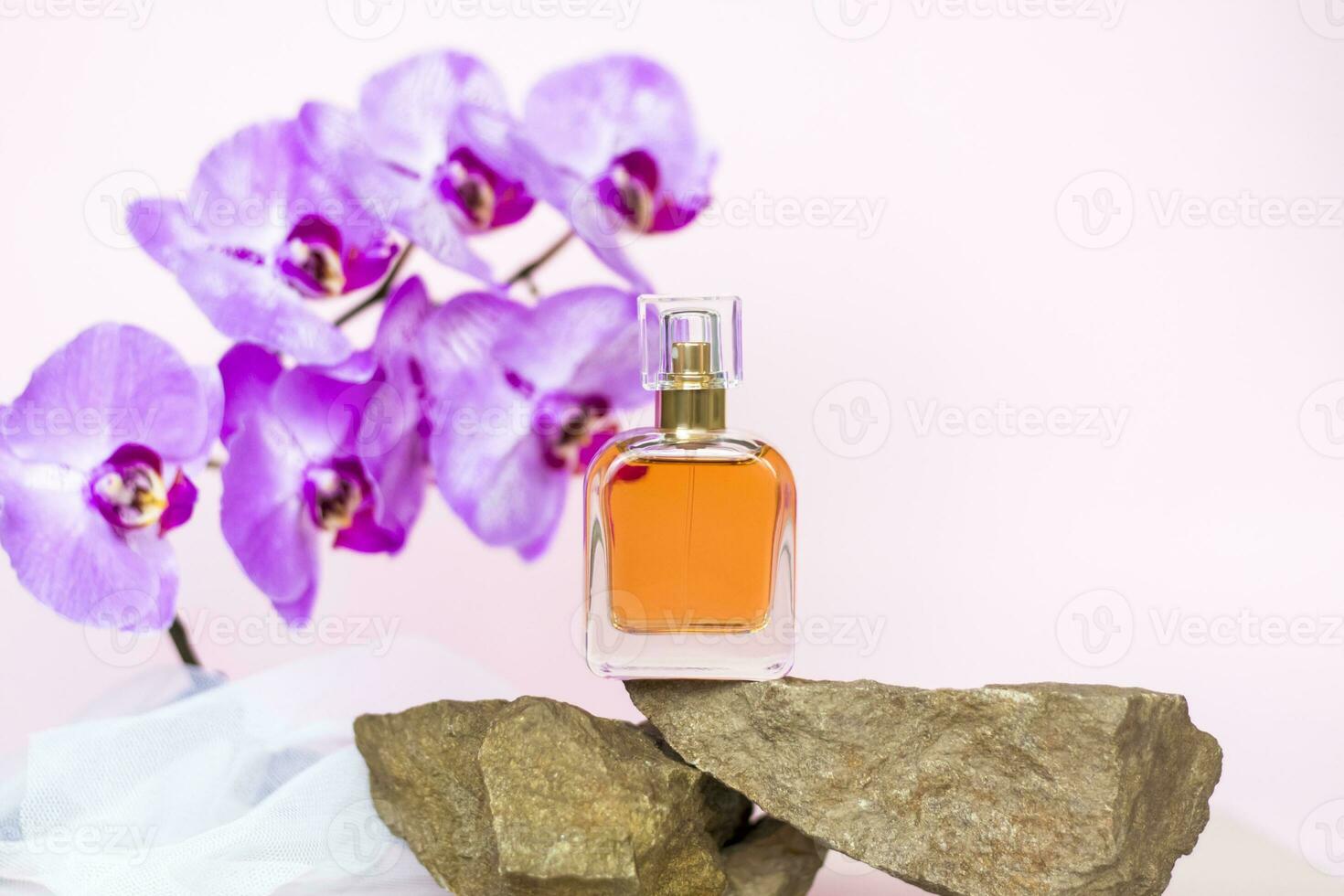 een parfum fles staat Aan een steen tegen een achtergrond van mooi orchideeën. elegant uiterlijk, lay-out, persoonlijkheid. banier, een plaats voor de tekst. foto