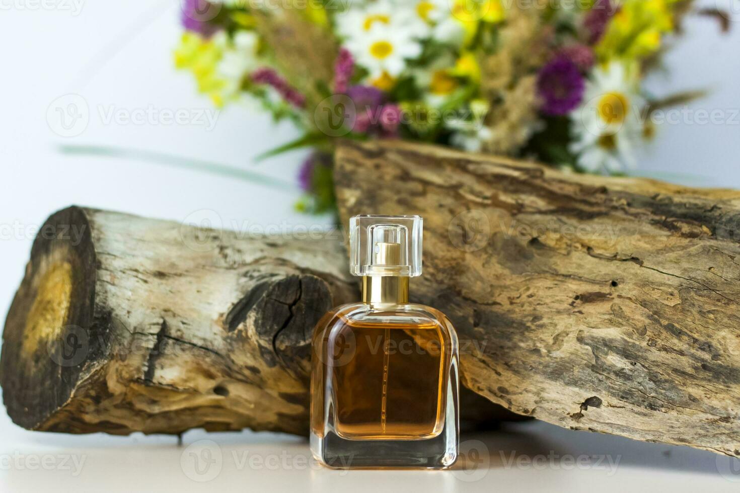 een parfum fles Aan de achtergrond van een droog stomp, boom schors en een boeket van wild bloemen. elegant uiterlijk, lay-out, persoonlijkheid. banier, een plaats voor de tekst. foto