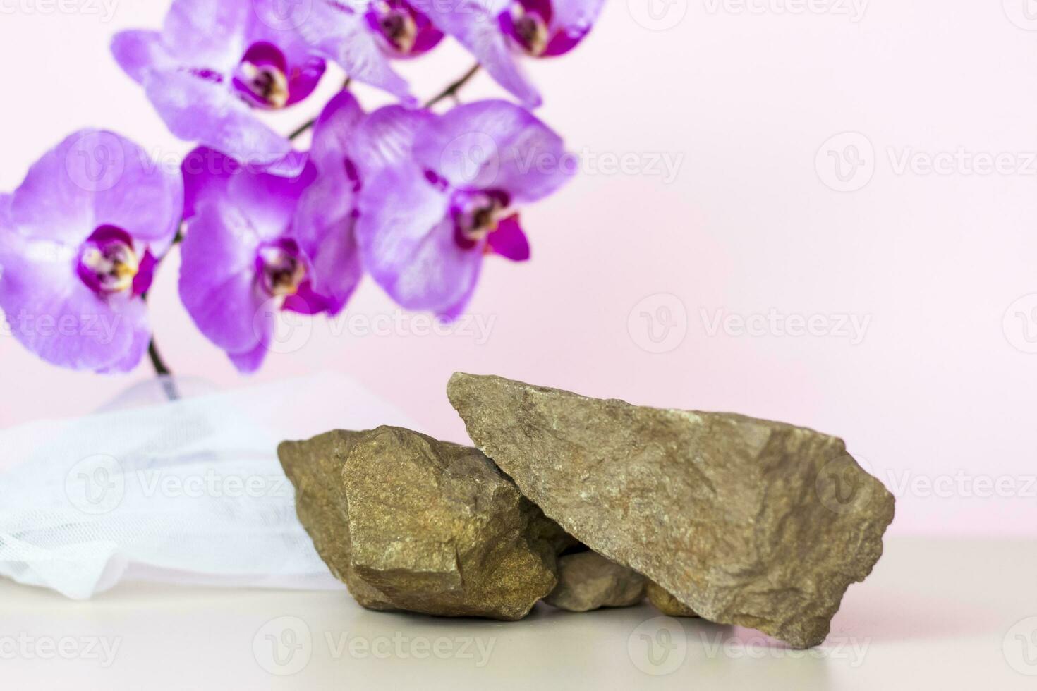 een teder achtergrond voor de presentatie van kunstmatig producten. stenen en orchidee bloemen. elegant uiterlijk, lay-out, persoonlijkheid. banier, een plaats voor de tekst. foto