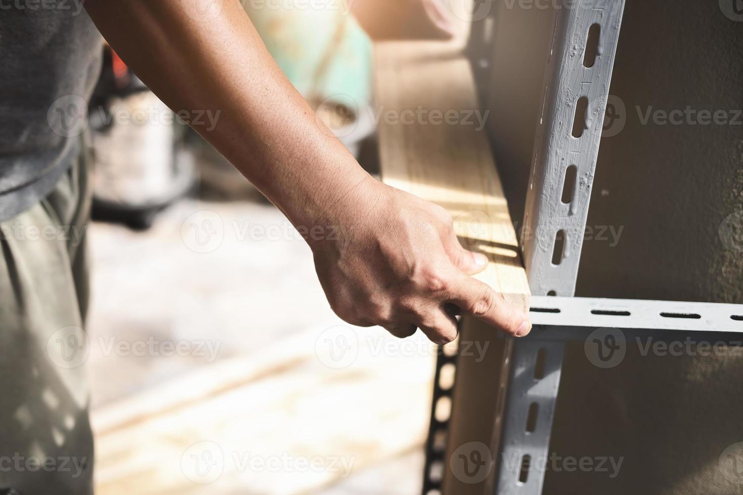 een vakman zet een houten plank op een stalen plank die hij in zijn vrije tijd in elkaar heeft gezet foto