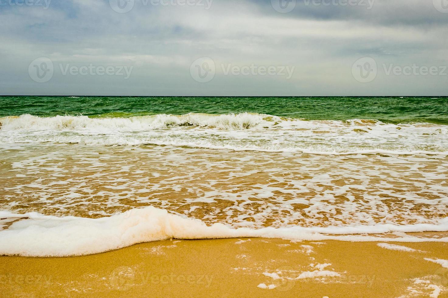 natuur zee lucht zand. zandstrand. schuim van de zee. zee textuur. zomervakantie zee concept. foto