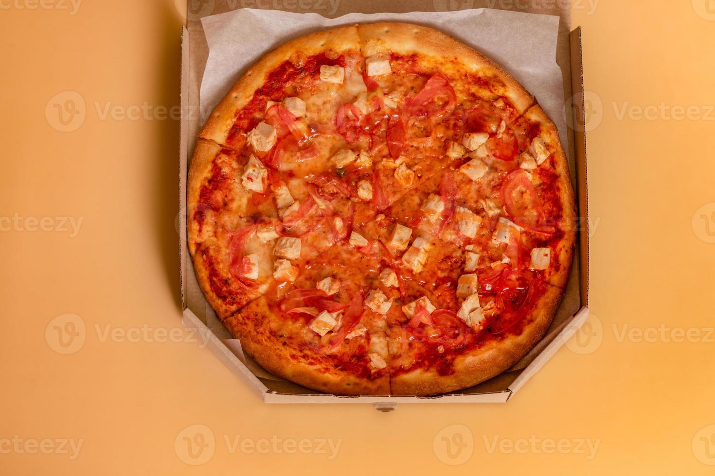 pizza op een beige achtergrond. afhaalmaaltijden. pizza in een kartonnen doos op de tafel in de keuken. foto