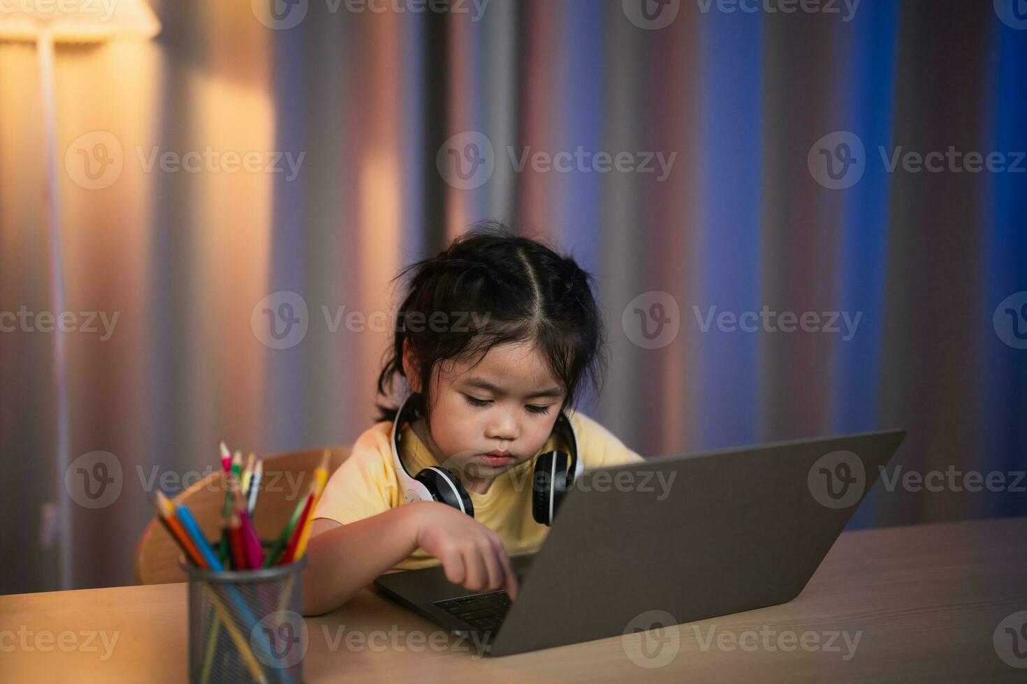 Aziatisch meisje lachend, lachend, opgewonden, op zoek, vervelend wit koptelefoon en gebruik makend van laptop streaming nacht licht in leven kamer Bij huis. schattig meisje aan het kijken videos terwijl TV internet verslaving concept. foto