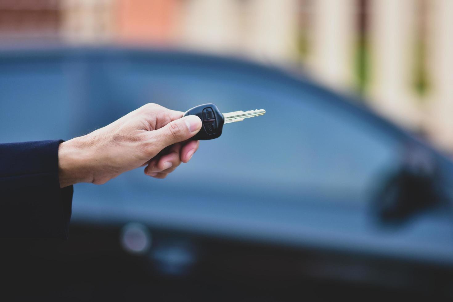 hand met sleutel en auto geparkeerde achtergrond foto