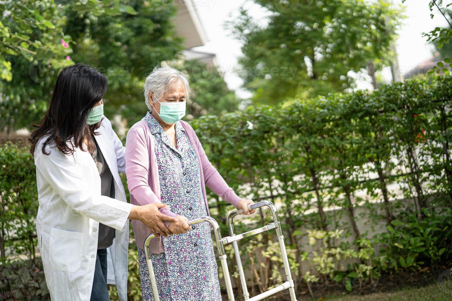 aziatische senior of oudere oude dame vrouw loopt met rollator en draagt een gezichtsmasker ter bescherming van de veiligheidsinfectie covid-19 coronavirus. foto
