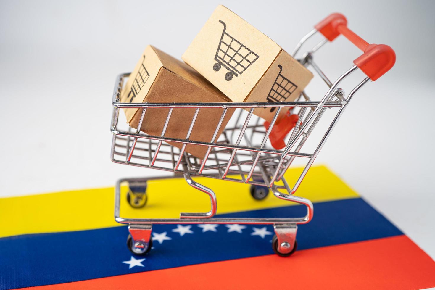 doos met winkelwagenlogo en vlag van venezuela, import export winkelen online of e-commerce financiën bezorgservice winkel product verzending, handel, leveranciersconcept. foto