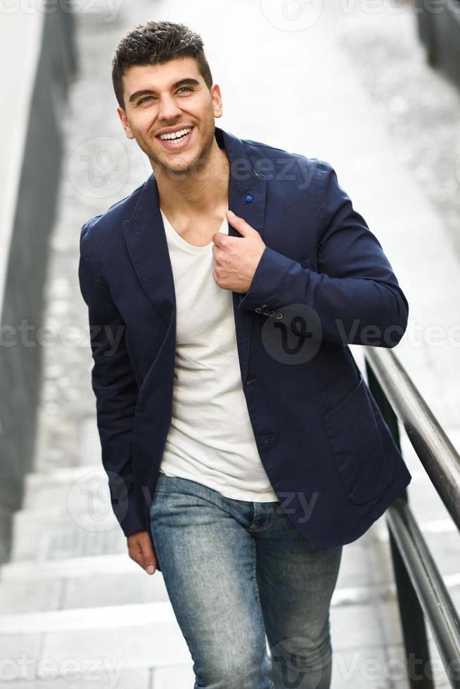 jonge man met blauwe ogen glimlachend in stedelijke achtergrond foto
