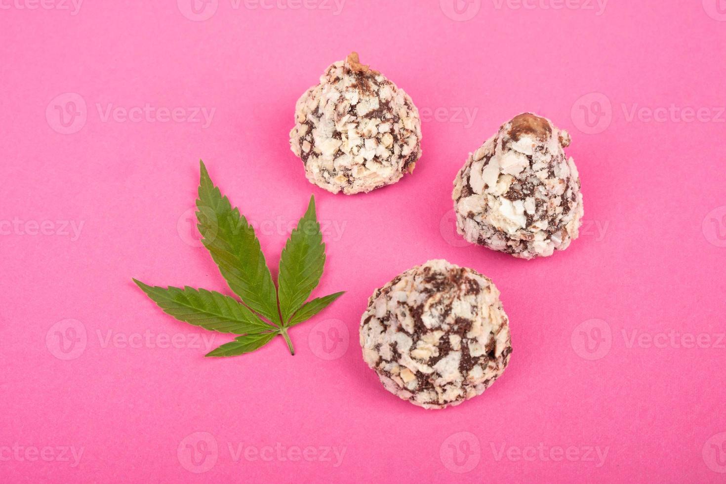 cannabis snoep chocolade truffel snoepjes met noten en groene bladmarihuana op roze achtergrond foto