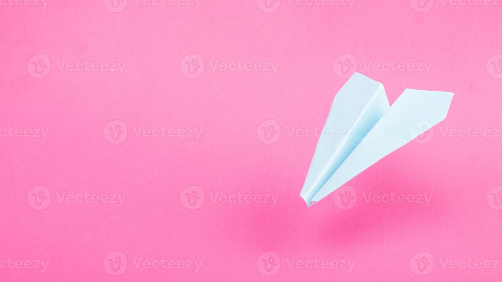 blauw origami-vliegtuig op roze achtergrond, reisvluchten kopiëren ruimte foto