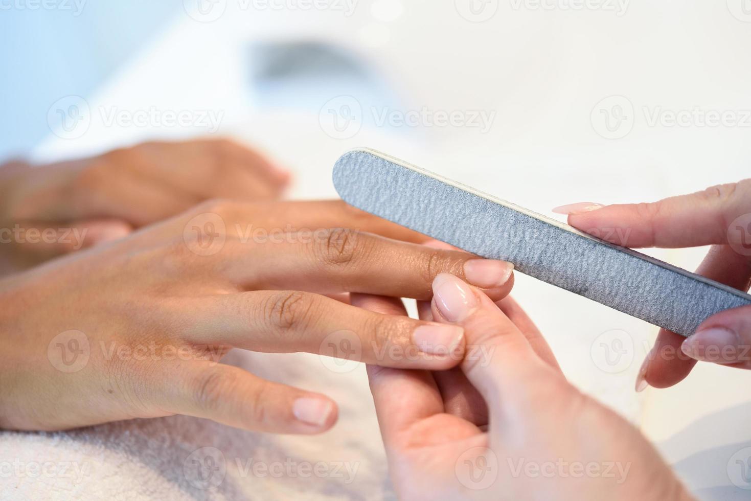 vrouw in een nagelsalon die een manicure met nagelvijl ontvangt foto