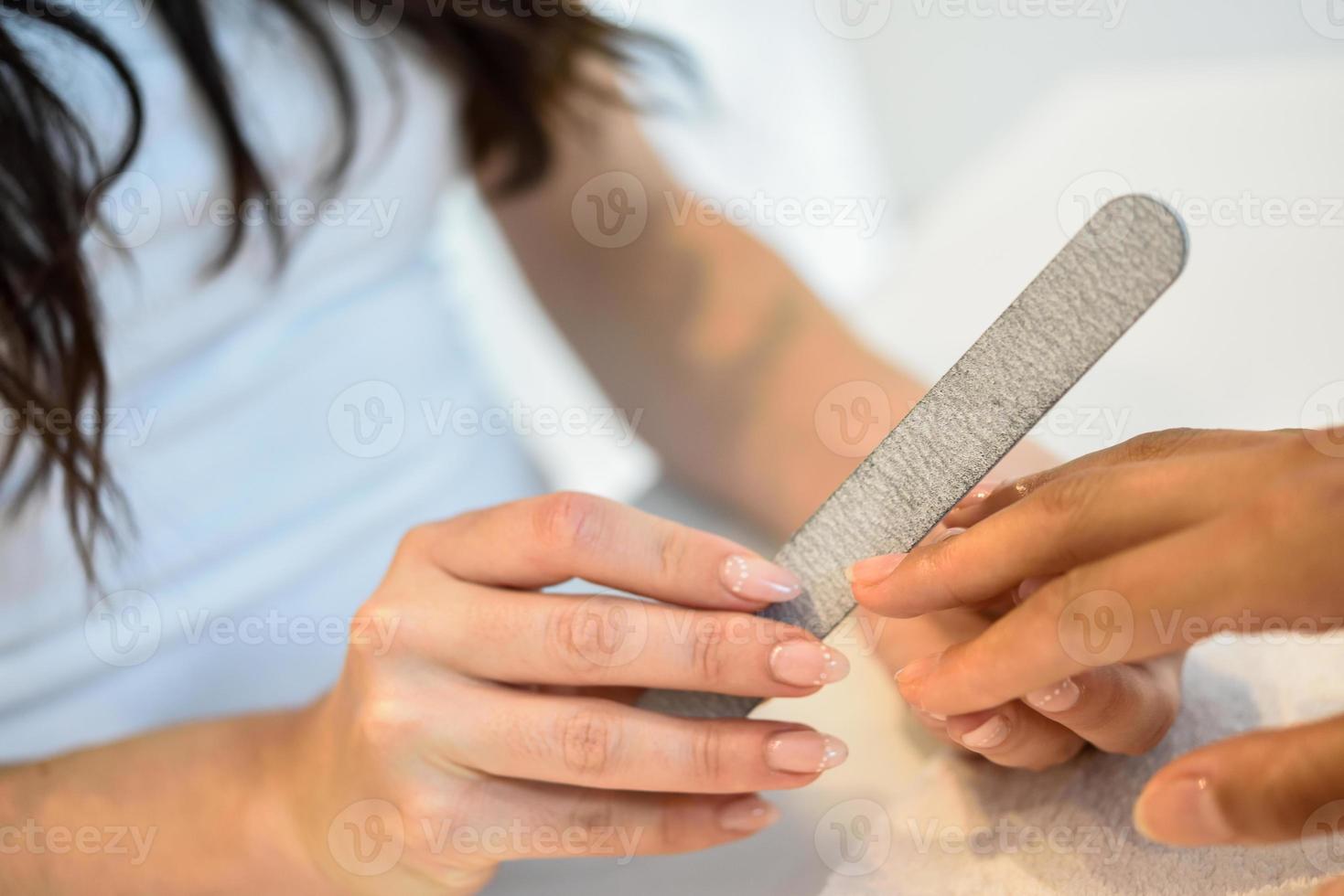 vrouw in een nagelsalon die een manicure met nagelvijl ontvangt foto