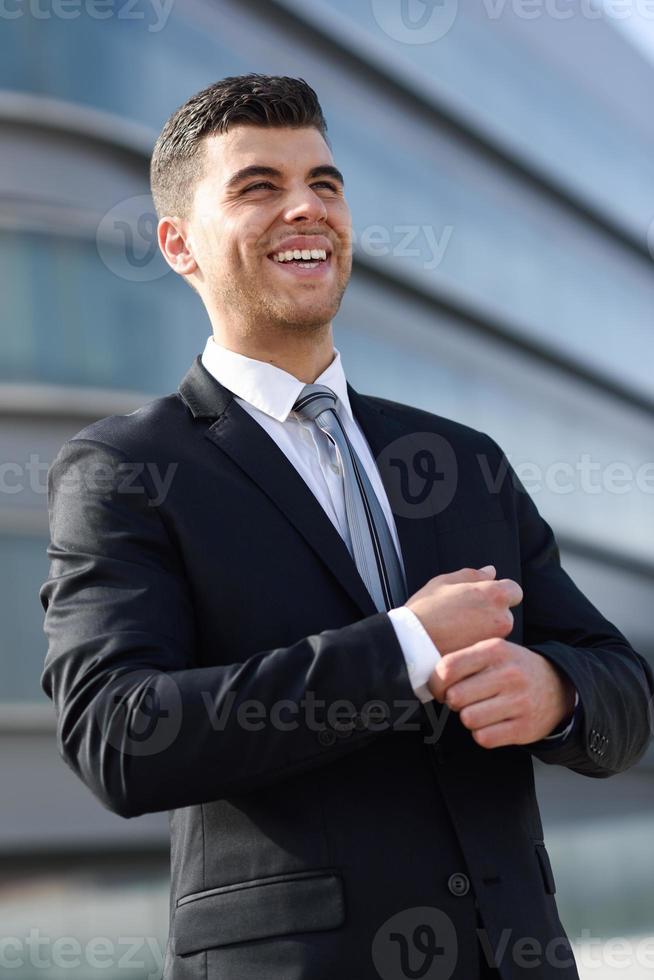jonge zakenman in de buurt van een kantoorgebouw in een zwart pak foto