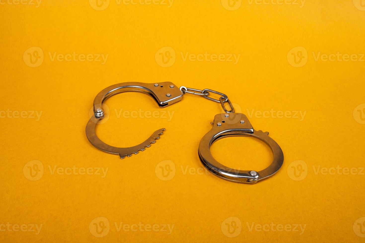 metalen handboeien op een gele achtergrond, concept van arrestatie foto