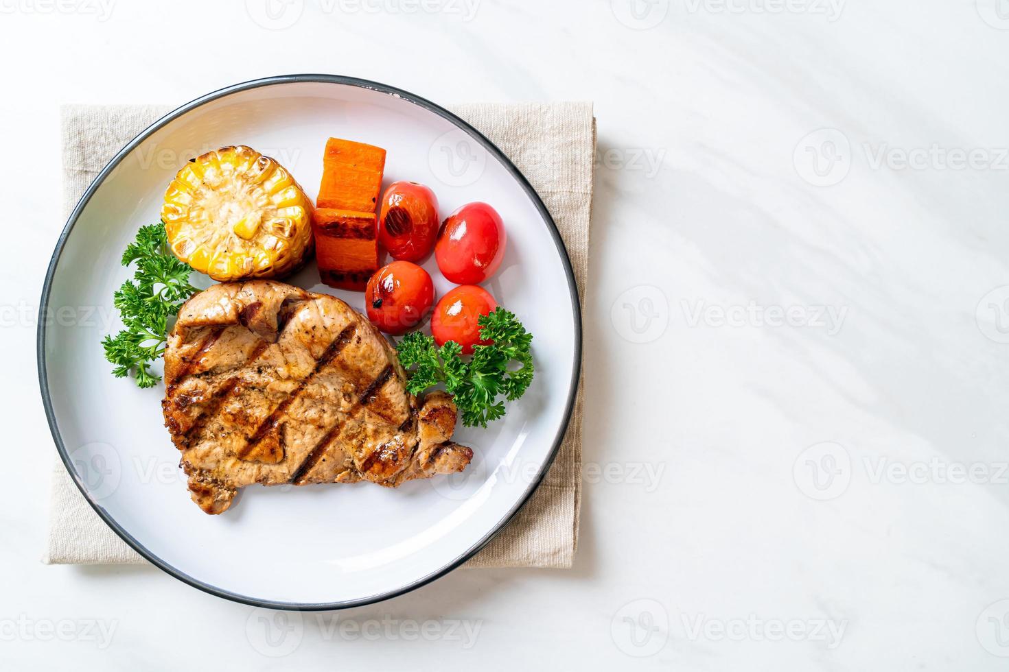 gegrilde en gebarbecued varkenshaasbiefstuk met maïs, wortel en tomaten and foto