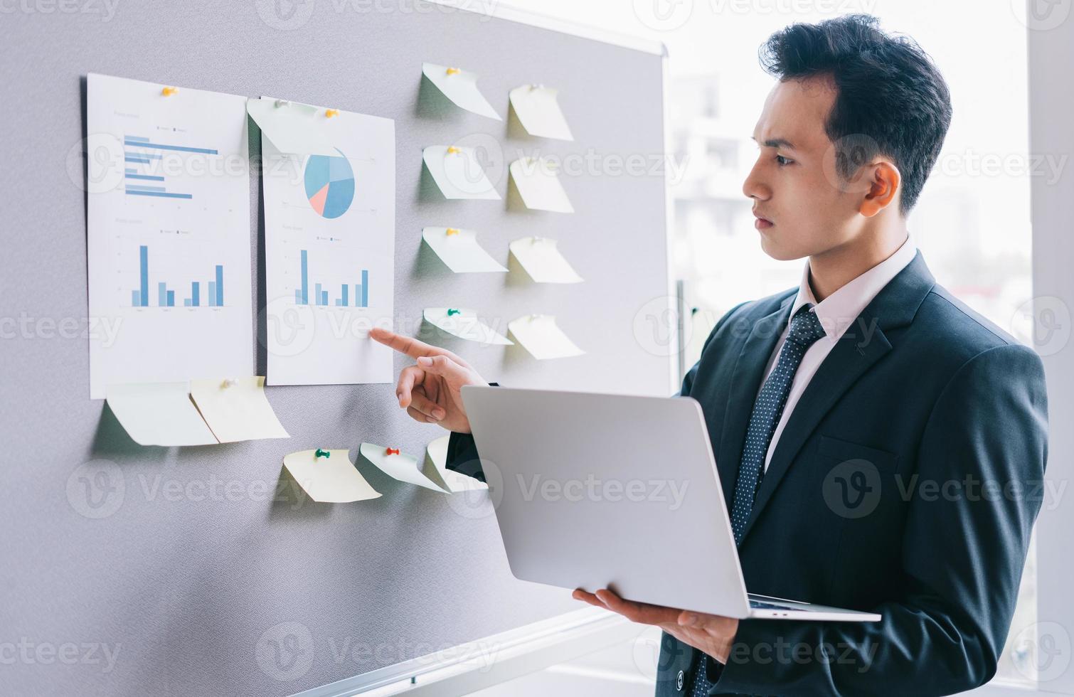 Aziatische zakenman die een bedrijf plant naast het planbord foto