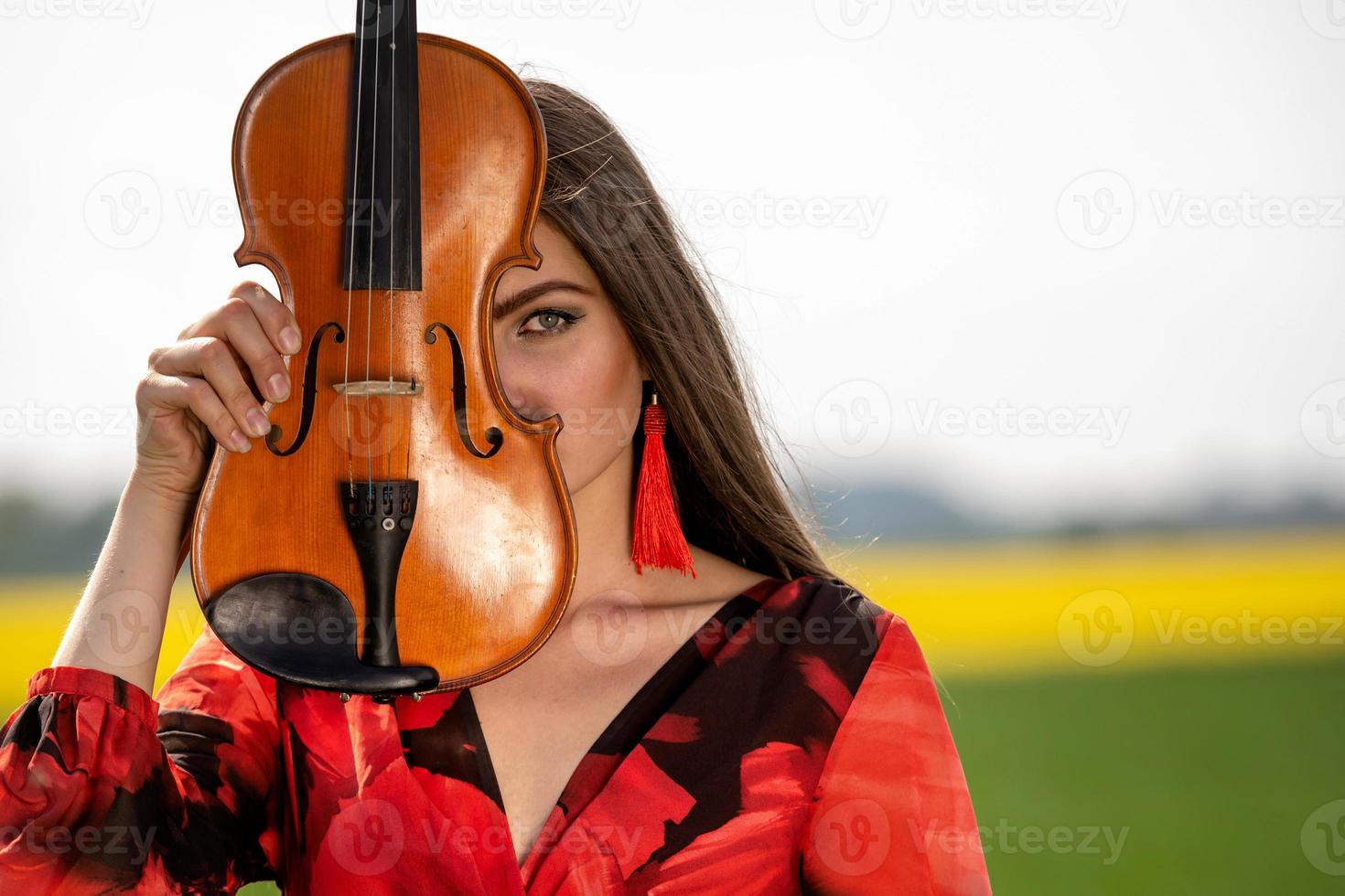 portret van een positieve jonge vrouw. een deel van het gezicht wordt bedekt door de hals van de viool - afbeelding foto