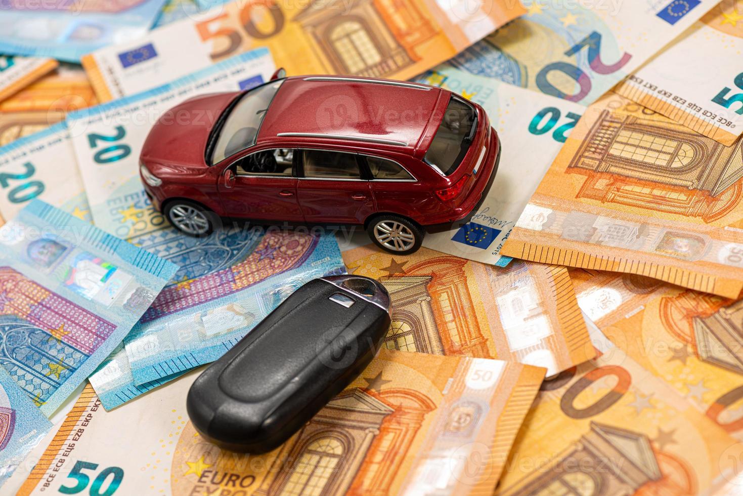 sleutel en rode speelgoedauto op stapel eurobankbiljetten foto