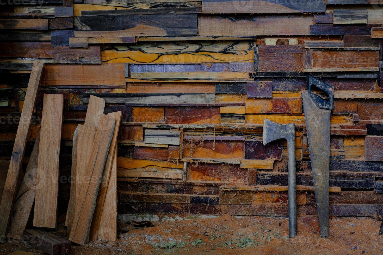 bijl met metalen handvat en handzaag die tegen oude muren rust, zijn gemaakt van verschillende houtsoorten foto