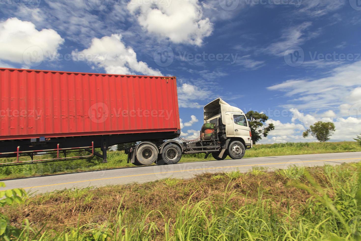 rode vrachtwagen op de snelweg onder de blauwe lucht foto