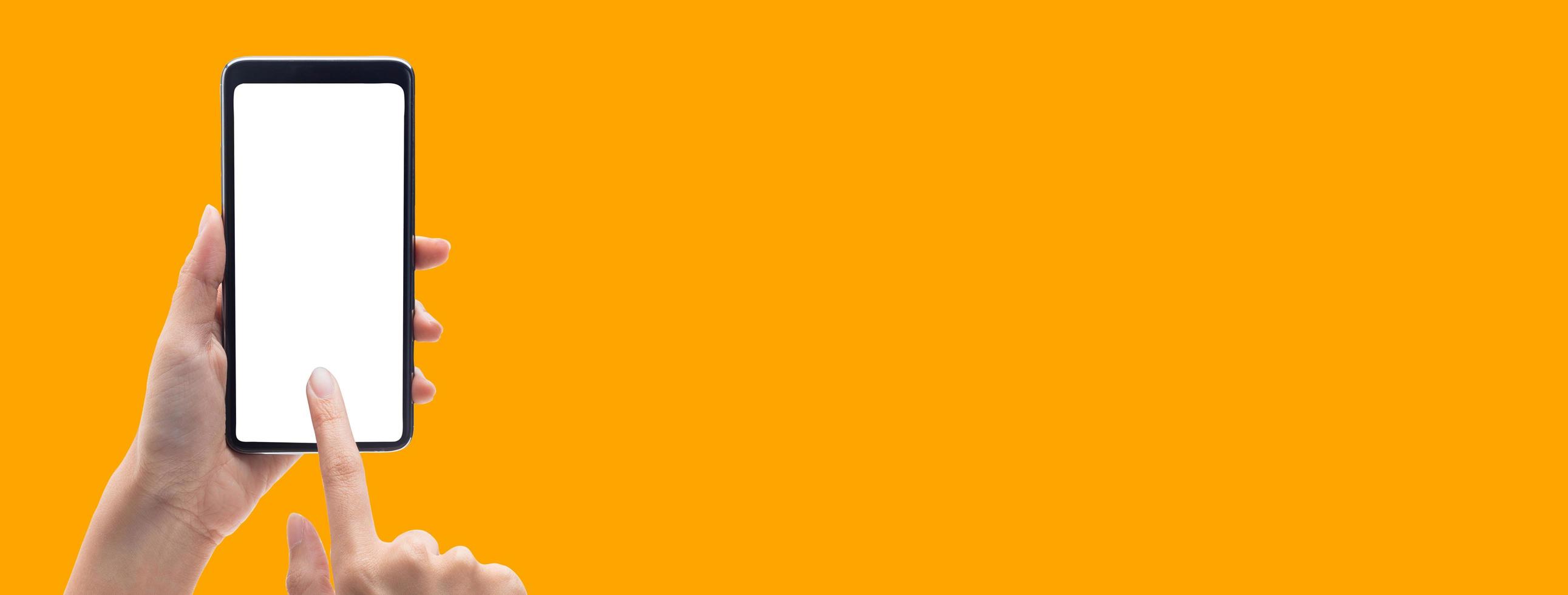 handen die smartphone op oranje bannerachtergrond gebruiken foto