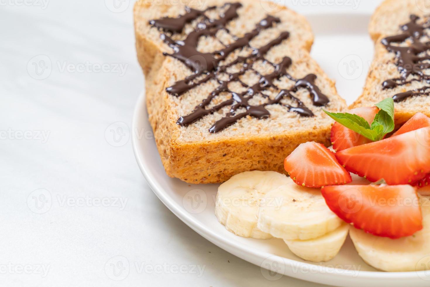 volkorenbrood geroosterd met verse banaan, aardbei en chocolade als ontbijt foto
