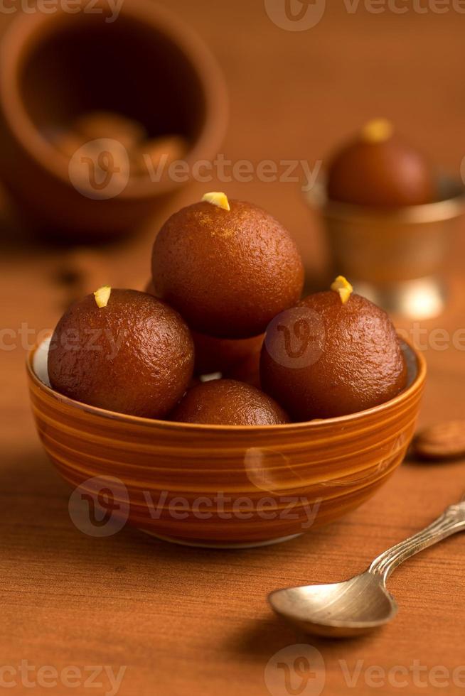 gulab jamun in kom en koperen antieke kom met lepel. Indiaas dessert of zoet gerecht. foto