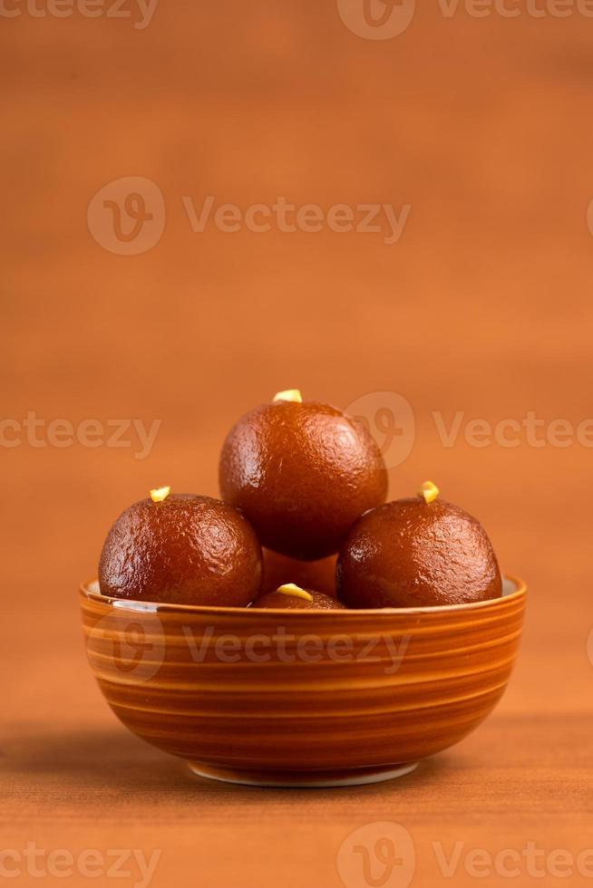 gulab jamun in kom op houten achtergrond. Indiaas dessert of zoet gerecht. foto