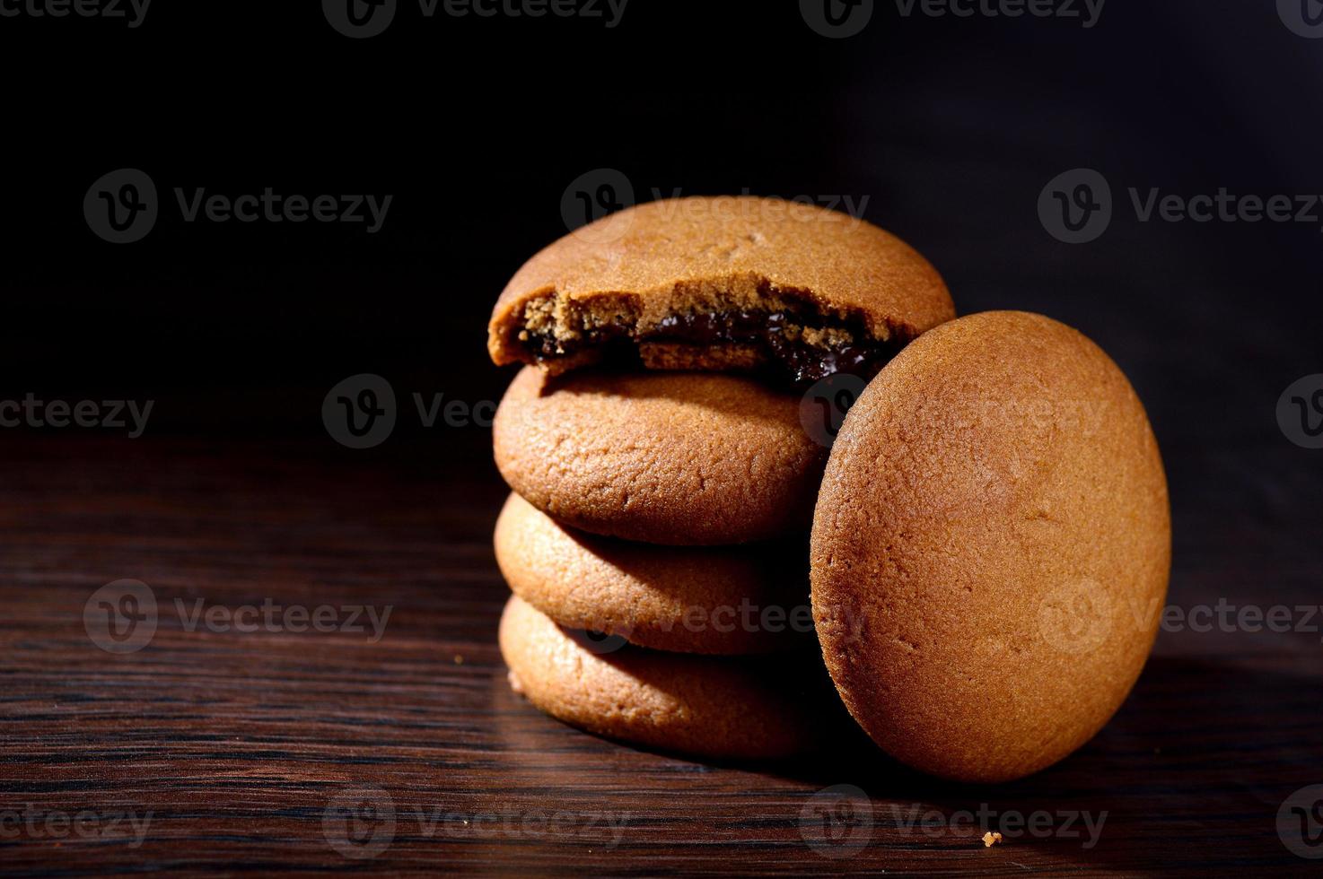 koekjes gevuld met chocoladeroom. chocolade crème koekjes. bruine chocoladekoekjes met roomvulling op zwarte achtergrond. foto