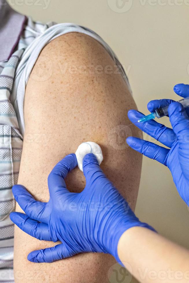 een arts vaccineert een man tegen het coronavirus in een kliniek. detailopname. het concept van vaccinatie, immunisatie, preventie tegen covid-19. foto