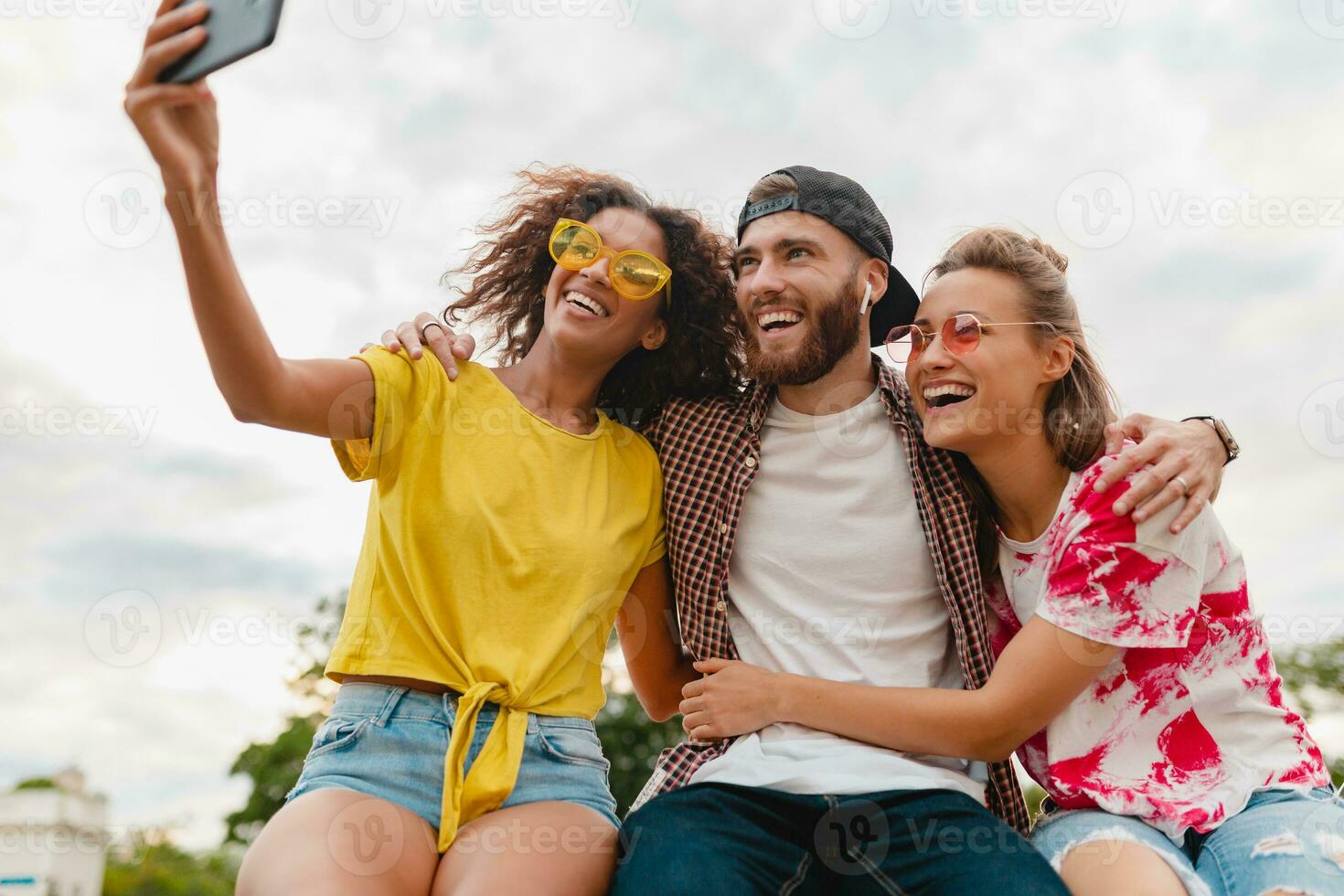 gelukkig jong bedrijf van glimlachen vrienden zittend in park foto