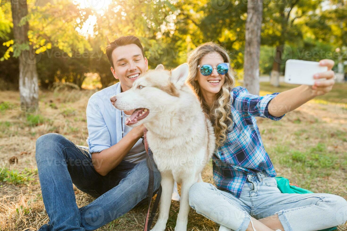 zonnig jong elegant paar spelen met hond in park foto