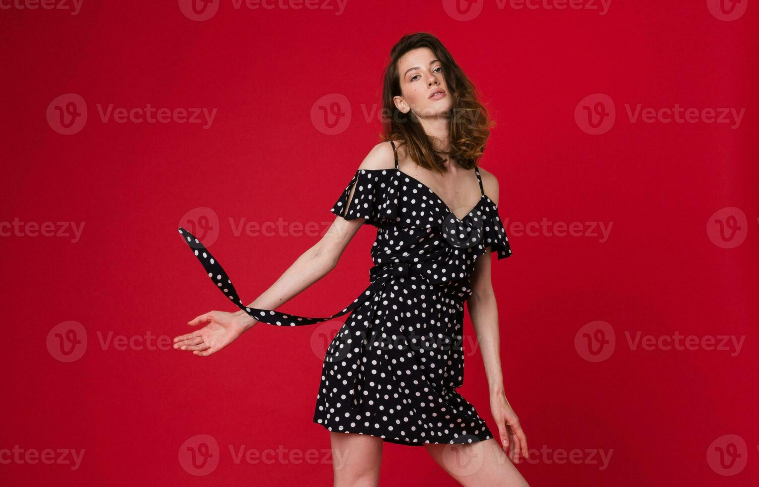 elegant vrouw in zomer mode neiging jurk Aan rood achtergrond foto