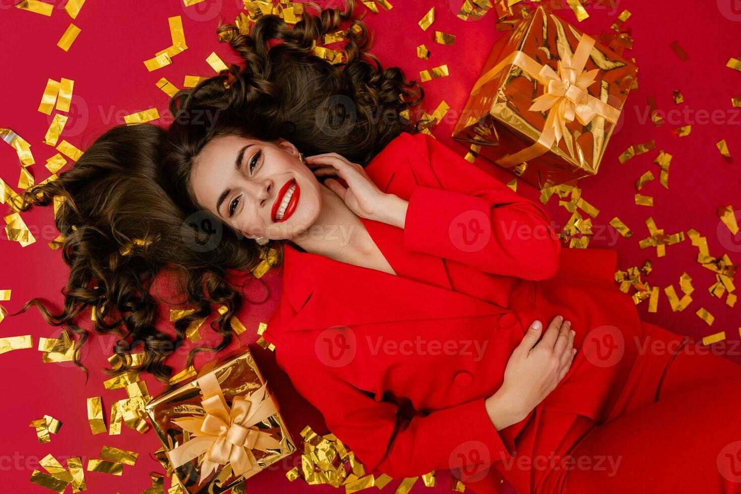 aantrekkelijk vrouw vieren Kerstmis Aan rood achtergrond in confetti foto