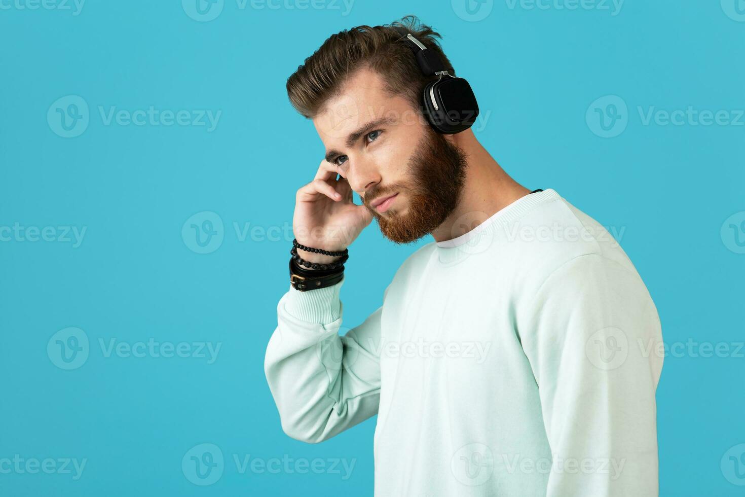 elegant jong Mens luisteren naar muziek- Aan draadloze hoofdtelefoons foto